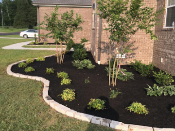 residential flower bed with fresh brown mulch and stone border 